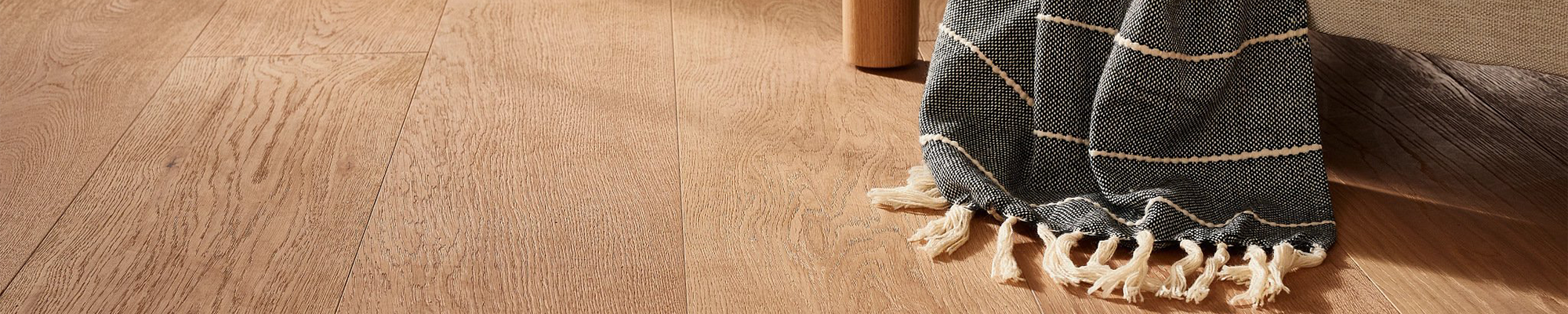 closeup of wood floors with throw on chair - Carpet For Less